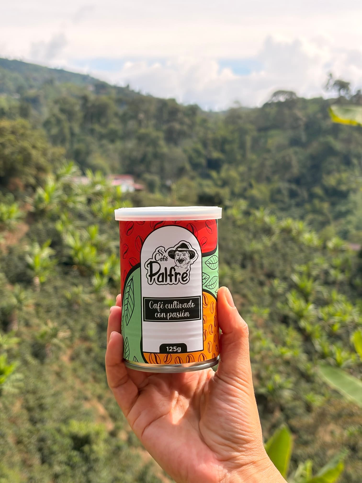 Lata de Café Palfré en la mano, frente a los cafetales de la finca
